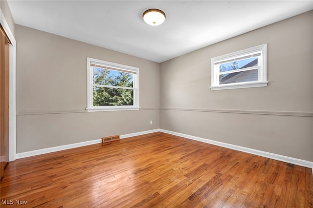 spare room featuring visible vents, baseboards, and wood finished floors