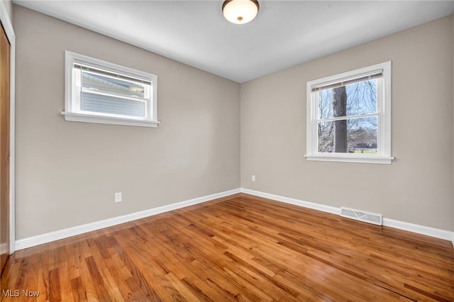 empty room featuring visible vents, baseboards, and wood finished floors