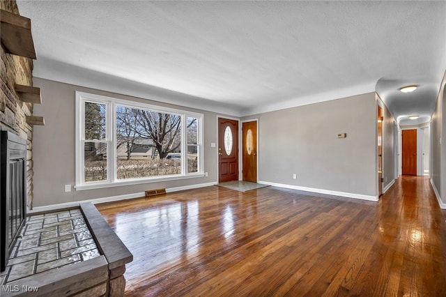 unfurnished living room with visible vents, wood-type flooring, baseboards, and a fireplace