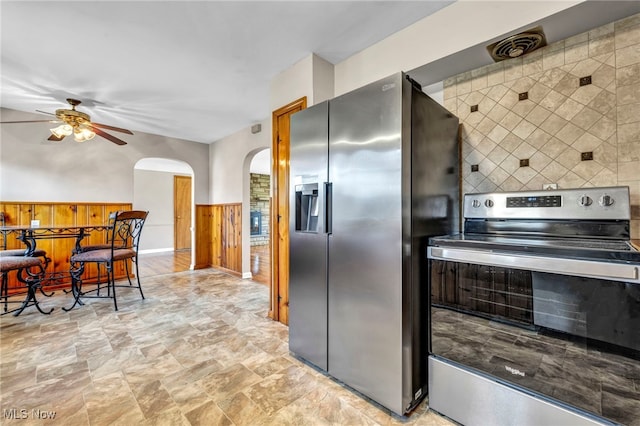 kitchen with arched walkways, backsplash, appliances with stainless steel finishes, and a ceiling fan