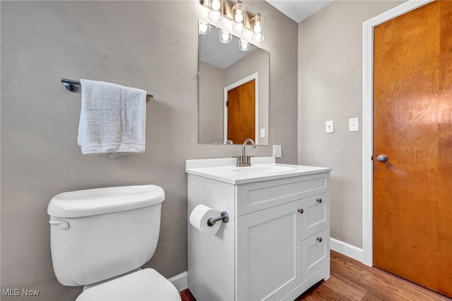 bathroom featuring baseboards, toilet, wood finished floors, and vanity