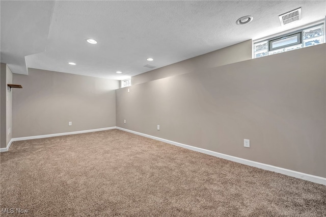 basement with recessed lighting, a textured ceiling, baseboards, and carpet