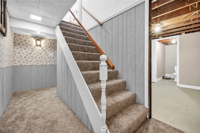 staircase with wood walls and carpet floors