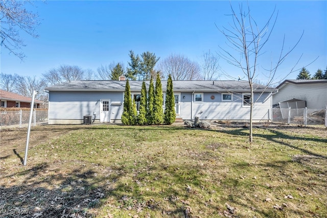 rear view of property featuring cooling unit, a chimney, a yard, and fence