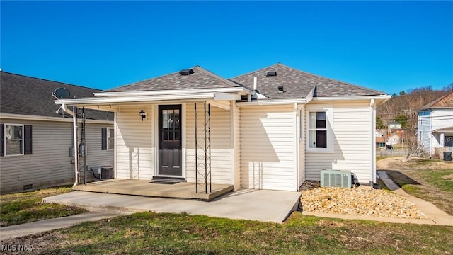 rear view of property featuring crawl space, central air condition unit, covered porch, and roof with shingles