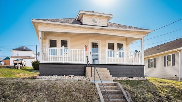 bungalow with covered porch, stairs, and roof with shingles