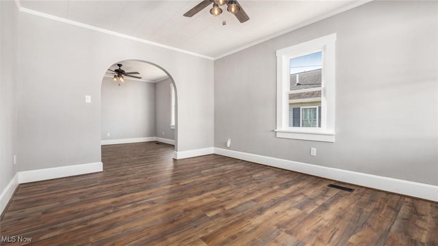 empty room with visible vents, arched walkways, dark wood-style floors, and crown molding