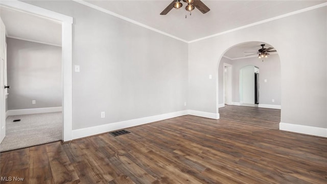 unfurnished room featuring arched walkways, crown molding, baseboards, and wood finished floors