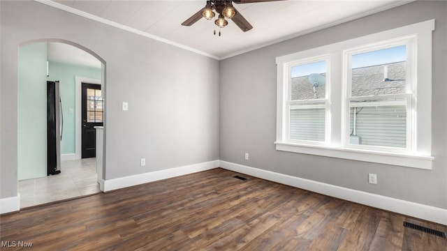 unfurnished room featuring arched walkways, visible vents, ornamental molding, and wood finished floors