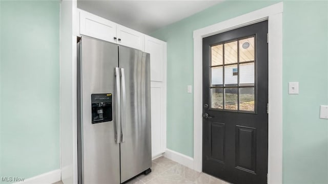 kitchen featuring white cabinetry, light tile patterned floors, baseboards, and stainless steel fridge