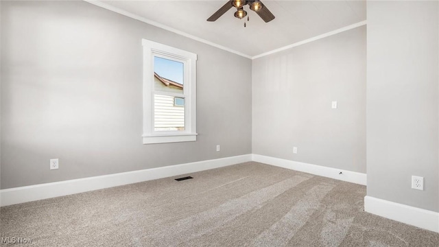 empty room with visible vents, ornamental molding, carpet flooring, baseboards, and ceiling fan