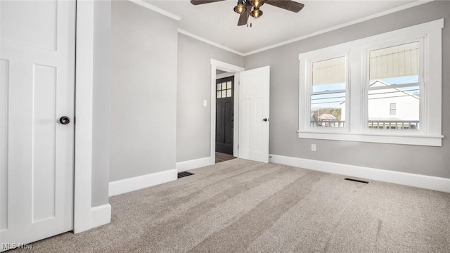 unfurnished bedroom featuring visible vents, baseboards, ornamental molding, and carpet flooring