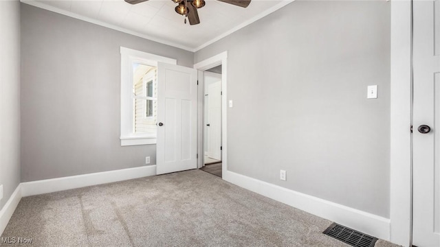 unfurnished bedroom with visible vents, carpet flooring, crown molding, and baseboards