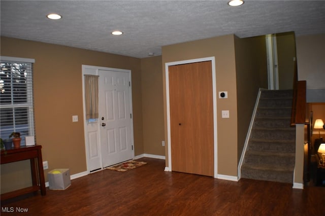 entrance foyer featuring stairway, baseboards, a textured ceiling, and wood finished floors