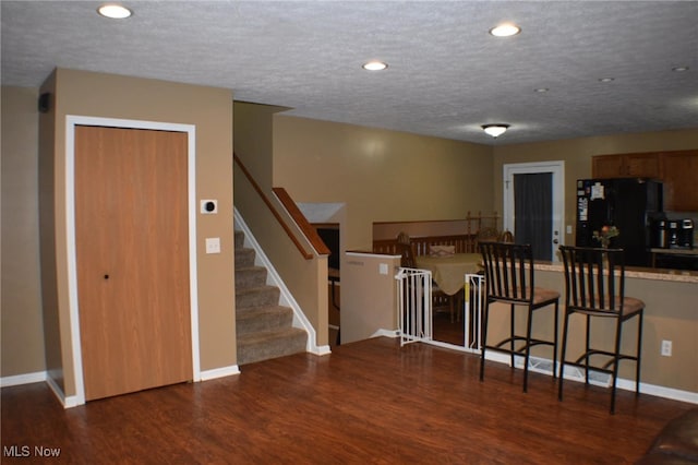 kitchen with a breakfast bar area, wood finished floors, baseboards, recessed lighting, and freestanding refrigerator