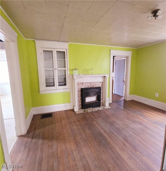 unfurnished living room featuring visible vents, a fireplace, baseboards, and hardwood / wood-style flooring