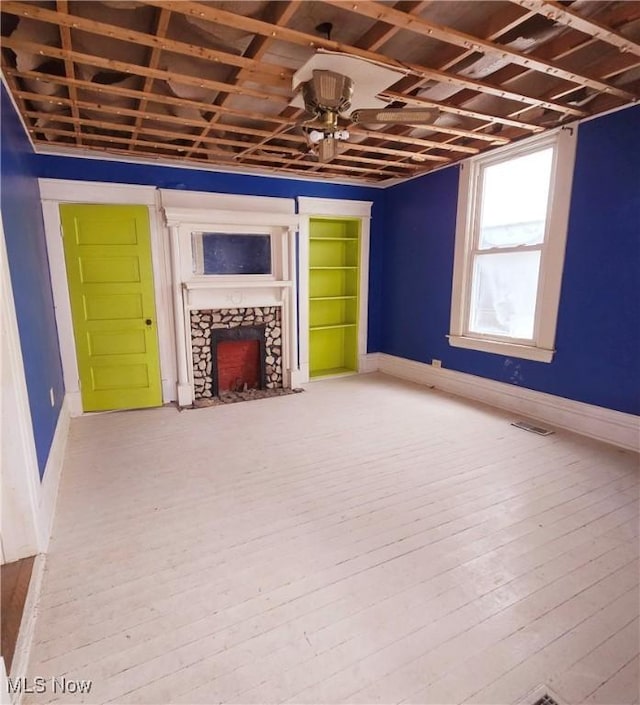 unfurnished living room with visible vents, baseboards, hardwood / wood-style floors, and a fireplace