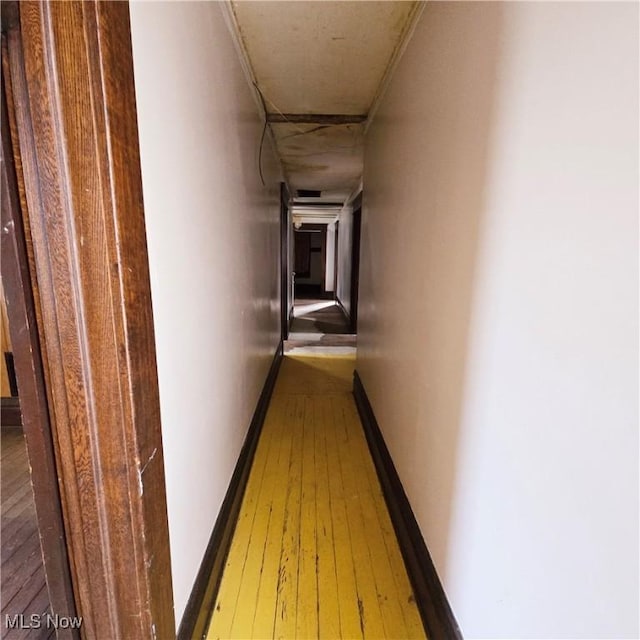 hallway featuring baseboards and wood-type flooring