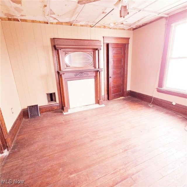 spare room featuring visible vents, wooden walls, wood finished floors, and baseboards