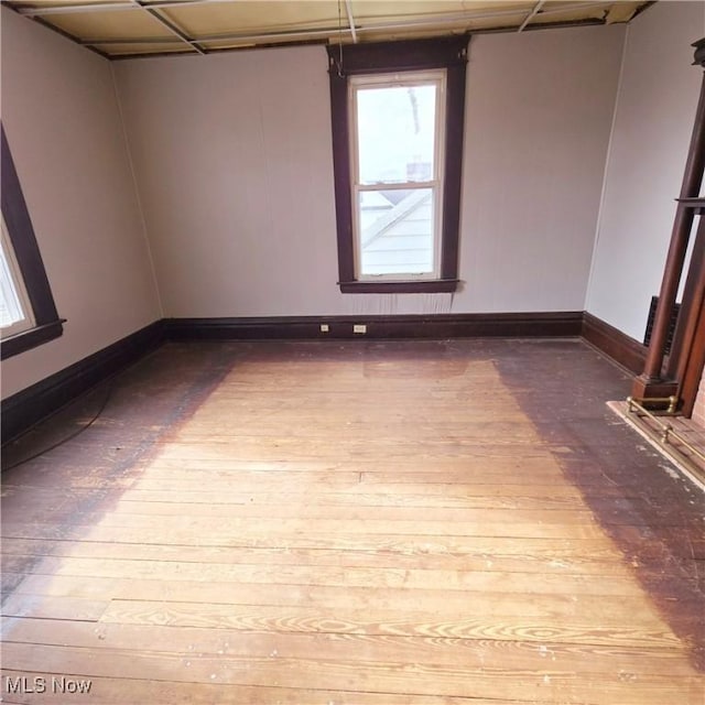 spare room featuring baseboards and hardwood / wood-style flooring