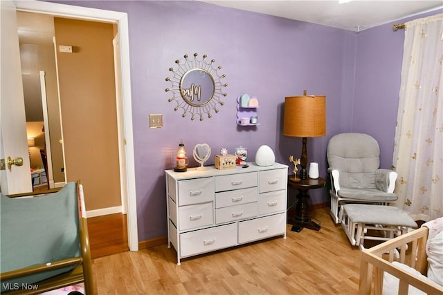 bedroom with a crib, baseboards, and light wood finished floors