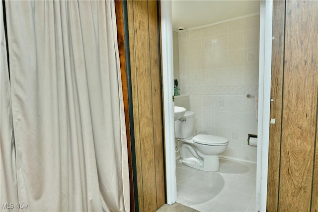 bathroom with tile patterned floors, toilet, and tile walls