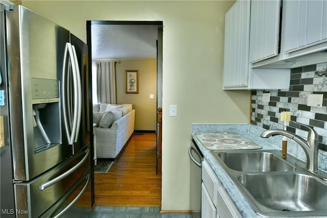 kitchen featuring a sink, stainless steel appliances, light countertops, white cabinets, and backsplash