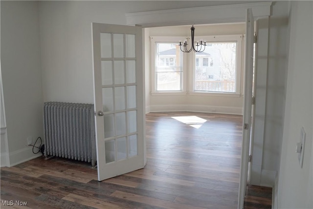 unfurnished dining area with an inviting chandelier, radiator, dark wood-type flooring, and baseboards