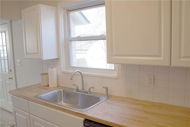 1341 Beach Ave, Lakewood, OH 44107 - kitchen featuring light countertops, white cabinets, backsplash, and a sink