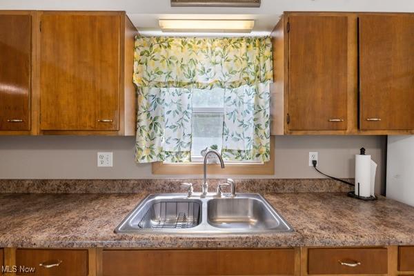 kitchen featuring brown cabinetry and a sink
