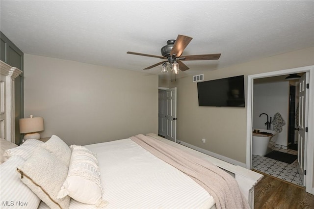 bedroom featuring visible vents, a textured ceiling, wood finished floors, baseboards, and ceiling fan