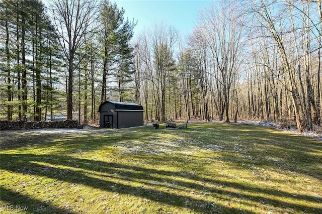 view of yard with an outdoor structure, a storage unit, and a forest view