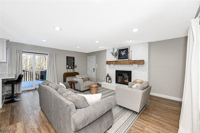 living room with wood finished floors, recessed lighting, a fireplace, and baseboards