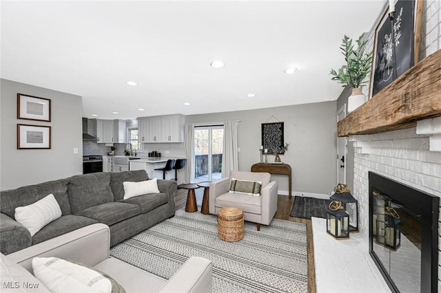 living room with a brick fireplace, recessed lighting, baseboards, and light wood-type flooring