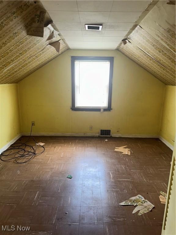 additional living space with visible vents, baseboards, and vaulted ceiling