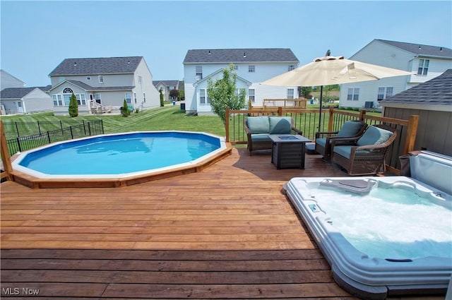 view of pool featuring fence, a wooden deck, a yard, a jacuzzi, and a residential view