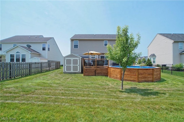 rear view of house with a fenced in pool, a lawn, a storage shed, a fenced backyard, and an outbuilding