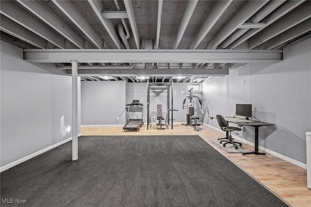 workout area with baseboards and wood finished floors