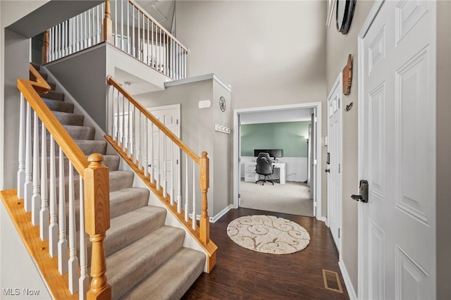 foyer entrance with visible vents, baseboards, a high ceiling, and wood finished floors