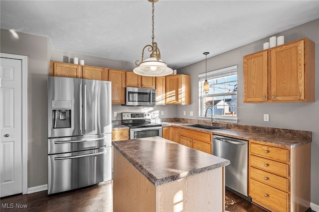 kitchen with a sink, stainless steel appliances, a kitchen island, and dark wood finished floors