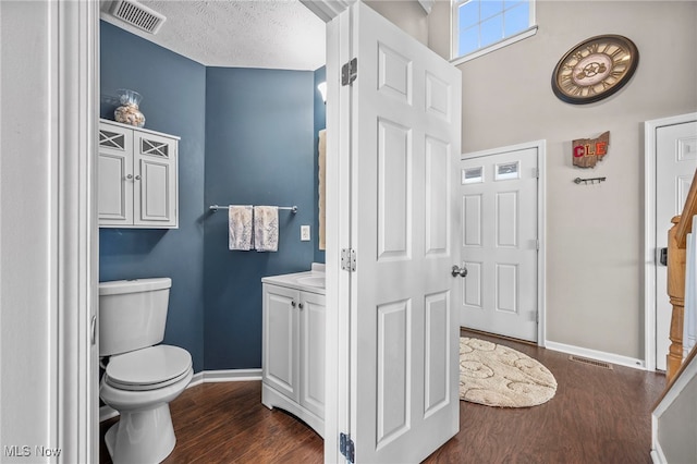 bathroom featuring toilet, wood finished floors, visible vents, and baseboards