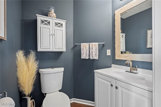 half bath featuring toilet, vanity, and baseboards