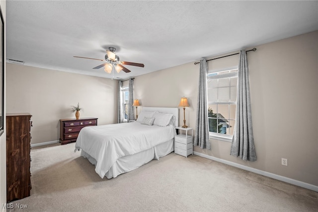 carpeted bedroom with ceiling fan, a textured ceiling, and baseboards