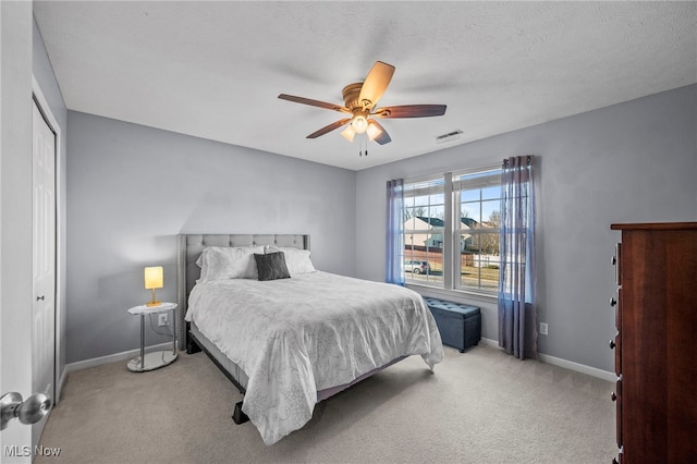 carpeted bedroom featuring a textured ceiling, baseboards, visible vents, and ceiling fan