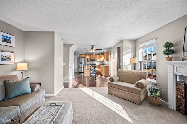 carpeted living room with a sink, baseboards, a textured ceiling, and a fireplace