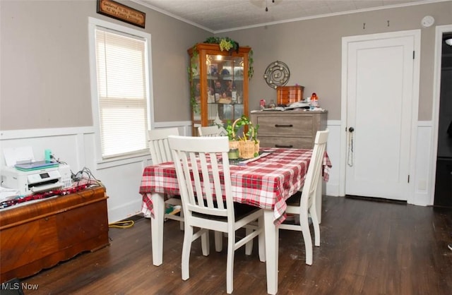 dining area with dark wood finished floors, ornamental molding, and wainscoting