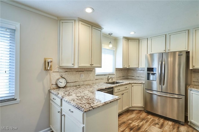 kitchen with stainless steel appliances, a peninsula, wood finished floors, and decorative backsplash