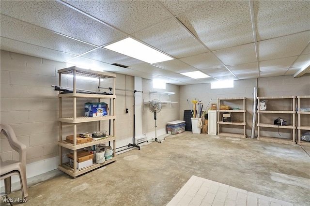 below grade area featuring a drop ceiling and concrete block wall