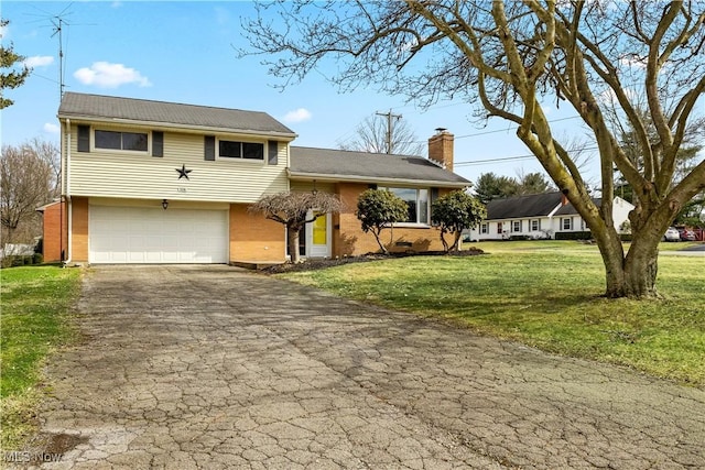 split level home featuring brick siding, driveway, a front yard, and a chimney