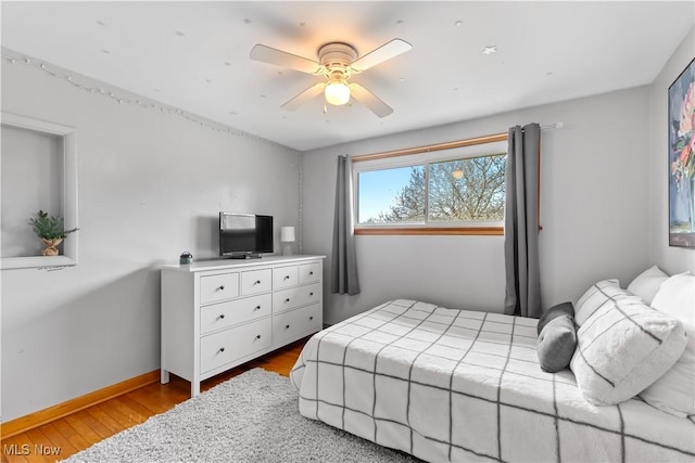 bedroom featuring ceiling fan, baseboards, and wood finished floors